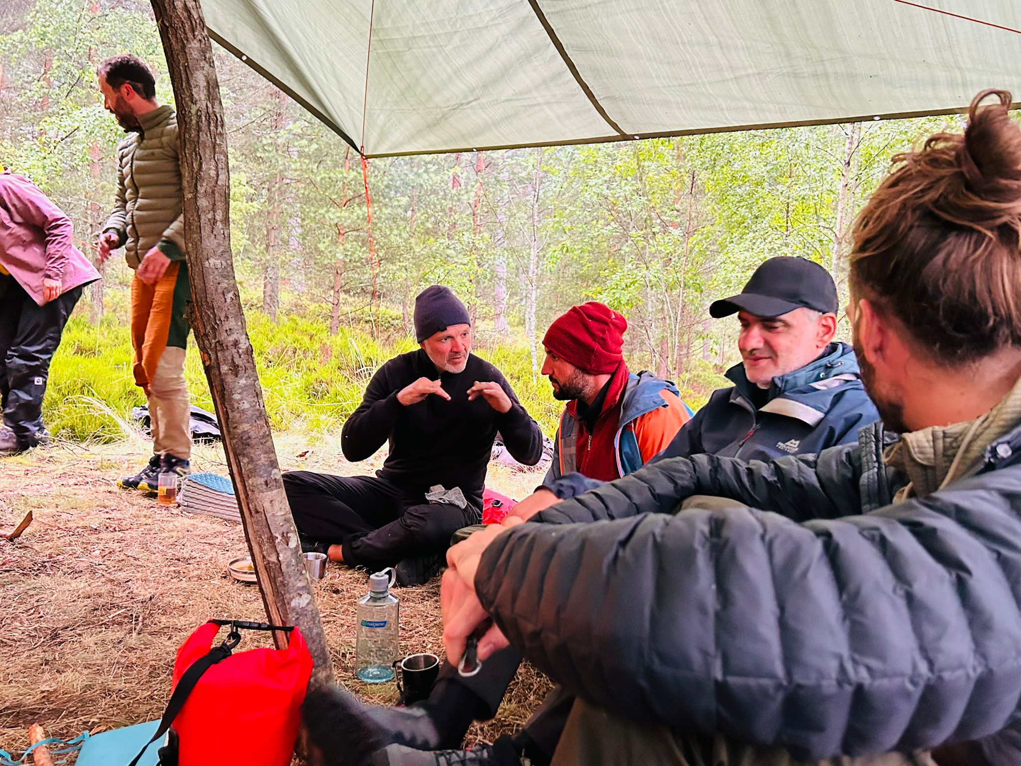Teilnehmende im Gespräch unter einer Plane beim Wald-Retreat