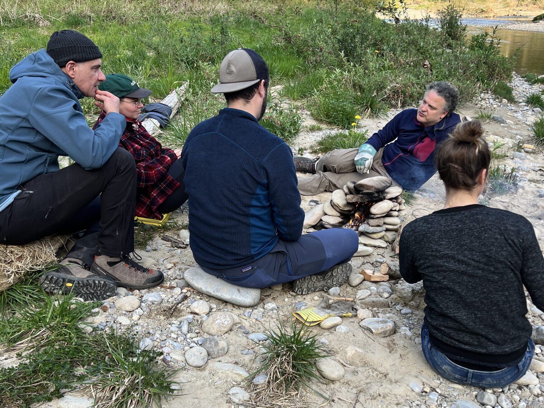 Gruppe sitzt und kocht mit Steinen über einem Feuer